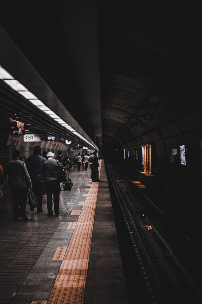Commuters wait on a dimly-lit train station platform, highlighting public transportation ambiance.