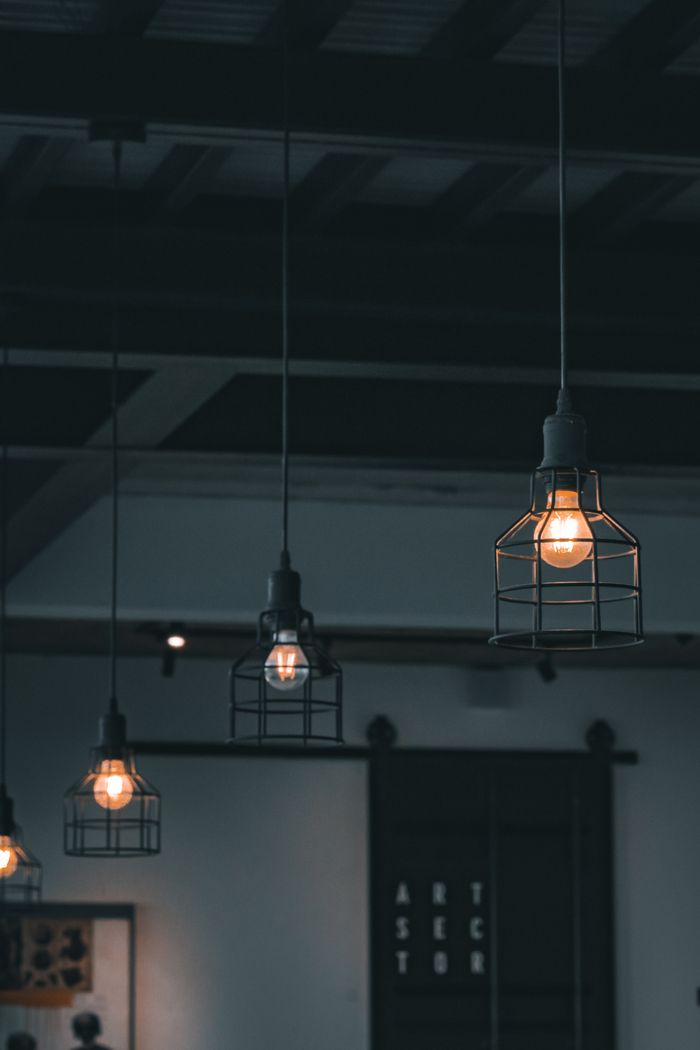 Stylish modern pendant lights with industrial design hanging in a moody urban interior setting.
